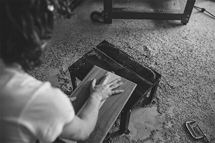 A worker sanding a timber panel on the atelier floor before frame assembly
